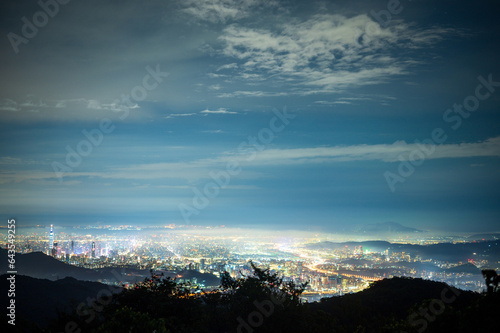 Urban Splendor at Night: Watching Dynamic Clouds Above a Dazzling Cityscape. View of the urban landscape from Dajianshan Mountain, New Taipei City, Taiwan. © twabian