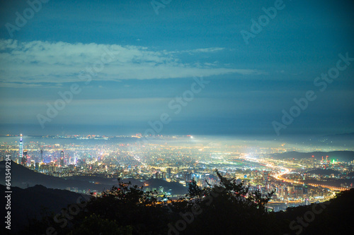 Nighttime Vista: Captivating City Lights and the Playful Dance of Clouds. View of the urban landscape from Dajianshan Mountain, New Taipei City, Taiwan. © twabian