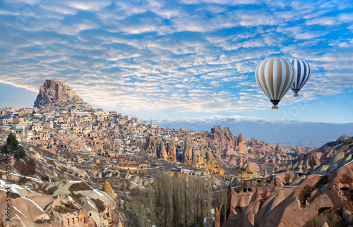 Hot air balloon flying over Pigeon Valley with Uchisar castle at bright cloudy sky - Cappadocia Turkey