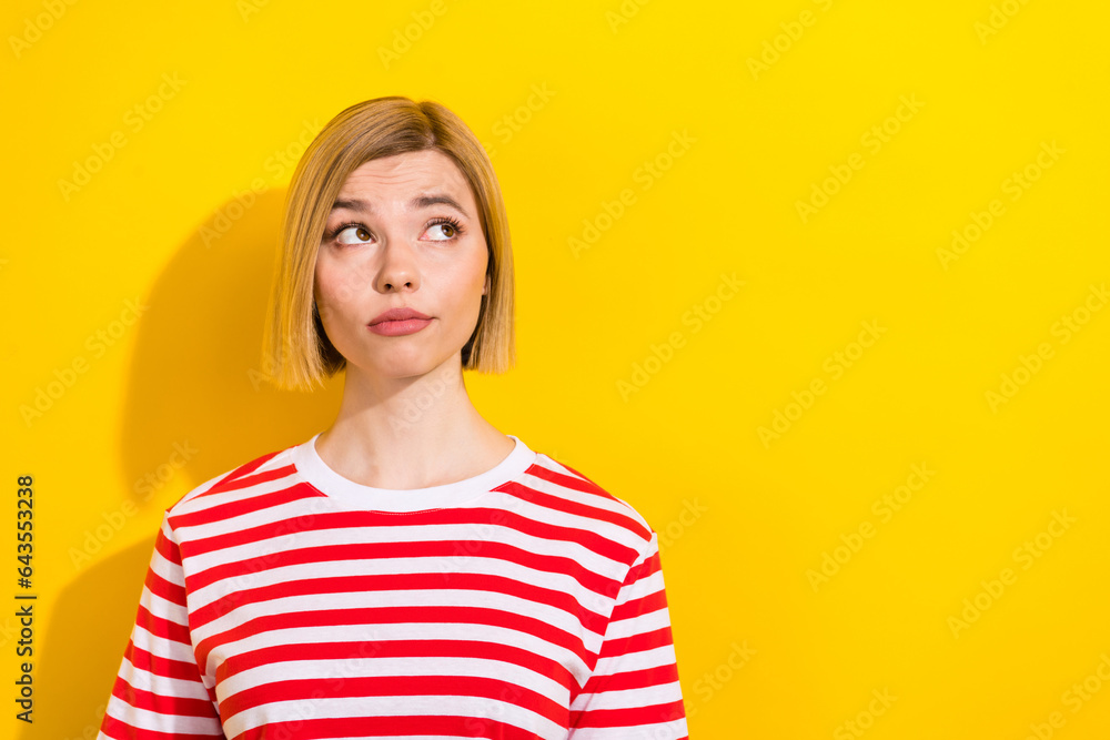 Photo of minded pretty lovely girl wear stylish clothes look up empty space choose product isolated on yellow color background Photo of minded pretty lovely girl wear stylish clothes look up empty space choose product isolated on yellow color background