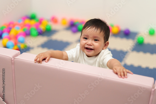 happy infant baby standing in fence of playpen