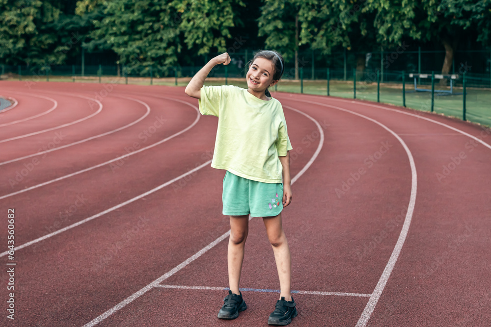 Obraz premium Strong little girl posing outdoors showing their muscles.