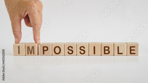 hand separated impossible to possible word on wooden cube block isolated background. For positive thinking, business strategy, enthusiastic, mindset concept