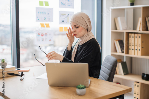 Fotografie Overworked lady massaging nose from destress at office desk