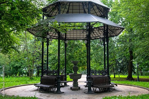 Openwork gazebo for relaxation with benches and a source of drinking water in the Mariinsky Park in Kyiv photo