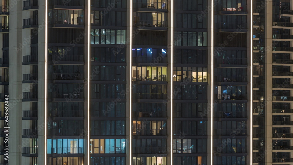 Tall blocks of flats with glowing windows located in residential district of city aerial timelapse.