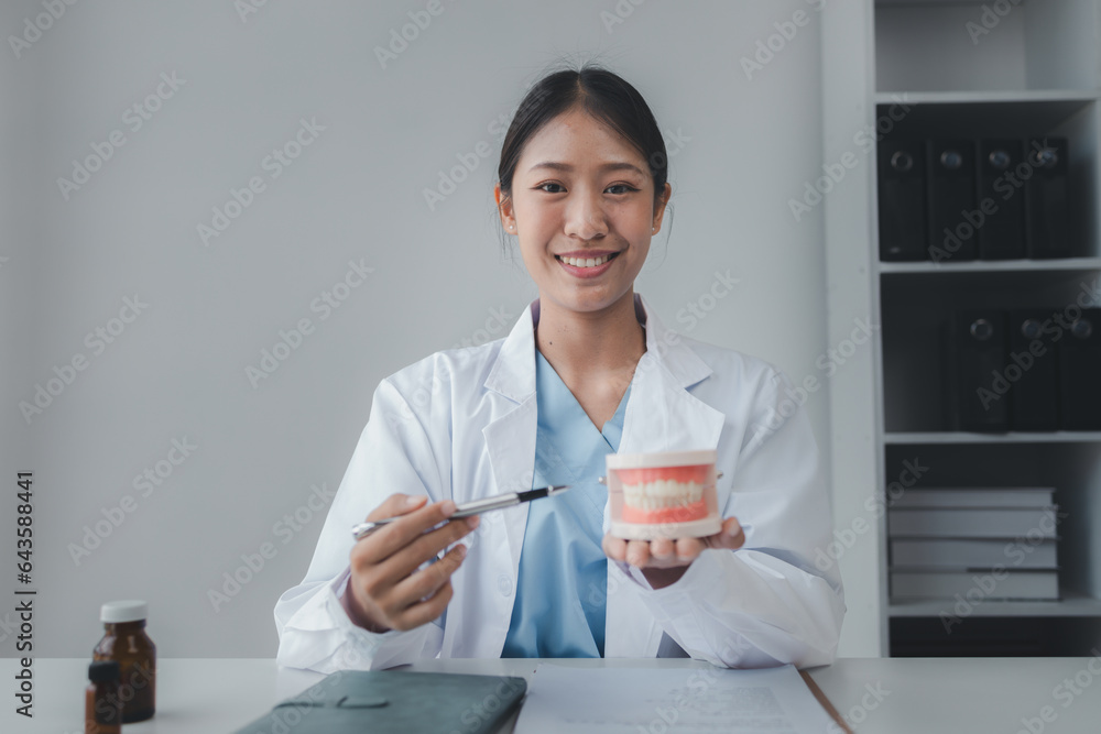Female dentist with dentures for explaining teeth, recommending