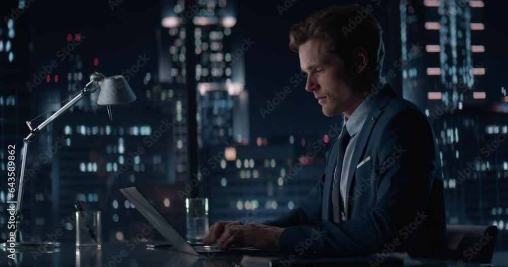 Successful Handsome Businessman Working on Laptop Computer in Big City Office Late in the Evening. Finance Investment Analyst Checking Financial Data from Project Management Report. Successful Handsome Businessman Working on Laptop Computer in Big City Office Late in the Evening. Finance Investment Analyst Checking Financial Data from Project Management Report.