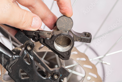 new brake pads in hand on the background of a bicycle brake caliper. Replacement of brake pads, close-up