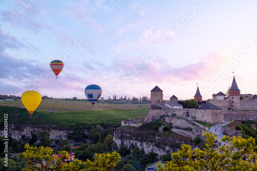 Beautiful sunset summer landscape with ancient castle and balloons in the sky. Kamianets-podilskyi, Ukraine.