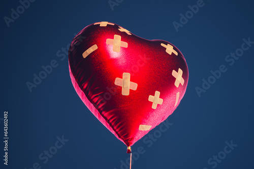 Red heart-shaped balloon fixed with bandaids. Broken heart remedy concept.