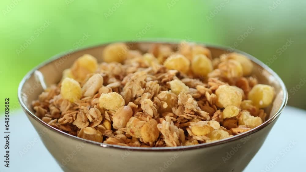 Bowl with oatmeal porridge, granola, cornflakes and almonds. Healthy breakfast food, clean eating, dieting concept, vegan diet. Muesli breakfast cereals close-up rotation slow motion. Food background Bowl with oatmeal porridge, granola, cornflakes and almonds. Healthy breakfast food, clean eating, dieting concept, vegan diet. Muesli breakfast cereals close-up rotation slow motion. Food background