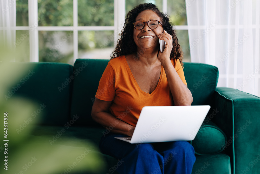 Happy mature woman calling her clients while working remotely Happy mature woman calling her clients while working remotely