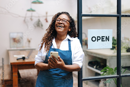 Successful small business owner holding a smartphone as she launches her shop