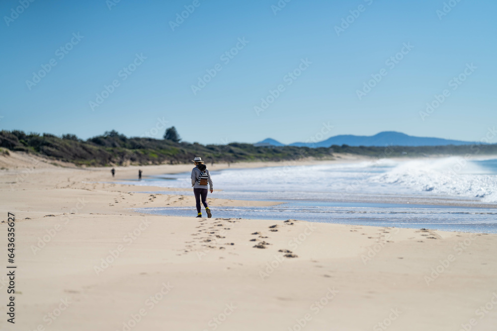 couple walking on the beach, women in coats and beanies walk down a winter beach in hobart tasmania, australia. couple walking on the beach, women in coats and beanies walk down a winter beach in hobart tasmania, australia.