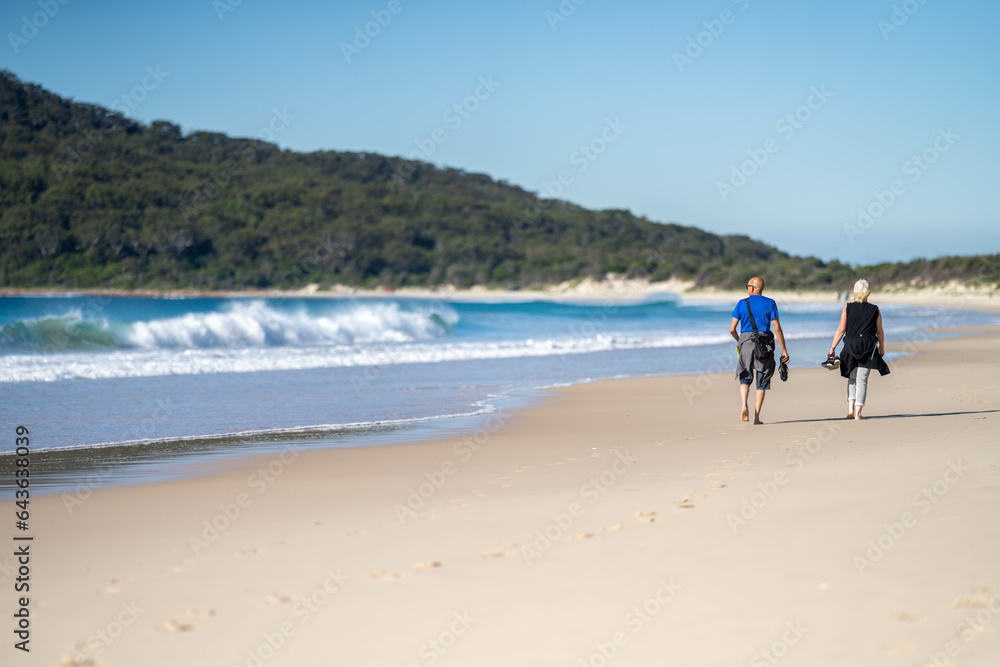 couple walking on the beach, women in coats and beanies walk down a winter beach in hobart tasmania, australia.