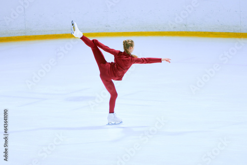 Talented girl, teenager in red sportswear, figure skating athlete in motion, training on ice rink arena. Concept of professional sport, competition, sport school, health, hobby, ad