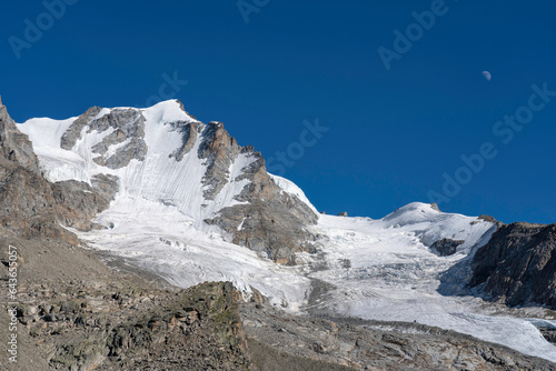 Gran Paradiso mountain and glacier view from chabod hut. white peak against blue sky with moon. landscape