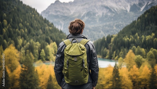 Hiking man with backpack looking at the lake and mountains in autumn