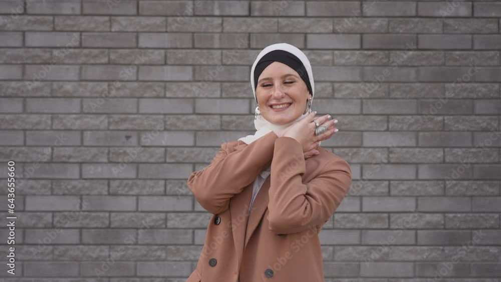 Portrait of a young blue-eyed woman in a hijab against a gray brick wall. Portrait of a young blue-eyed woman in a hijab against a gray brick wall.