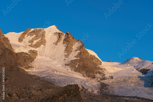 Gran Paradiso mountain and glacier view from chabod hut at sunset. golden hour, colored peak against blue sky. landscape