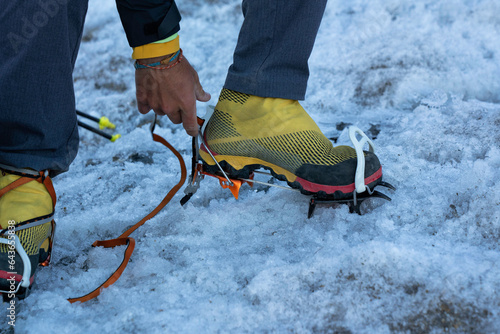 Mountaineer wearing the crampons to walk on the ice and climb the mountain glacier to the peak. close up details. Gran Paradiso National Park.