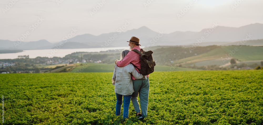 Senior couple standing in the middle of meadow and having romantic moment at the autumn nature.