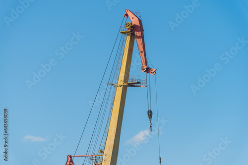 The boom of a large port cranes against a blue sky background,