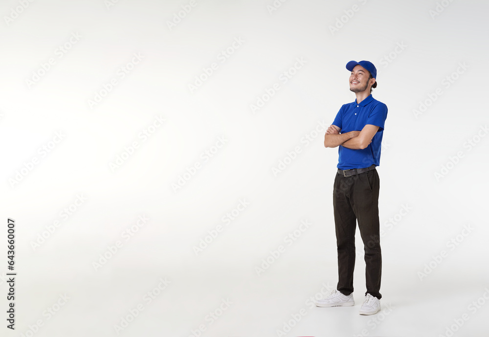 Smiling asian delivery man in blue uniform standing with arms crossed isolated on white background. looking up copy space. Full length portrait. Smiling asian delivery man in blue uniform standing with arms crossed isolated on white background. looking up copy space. Full length portrait.