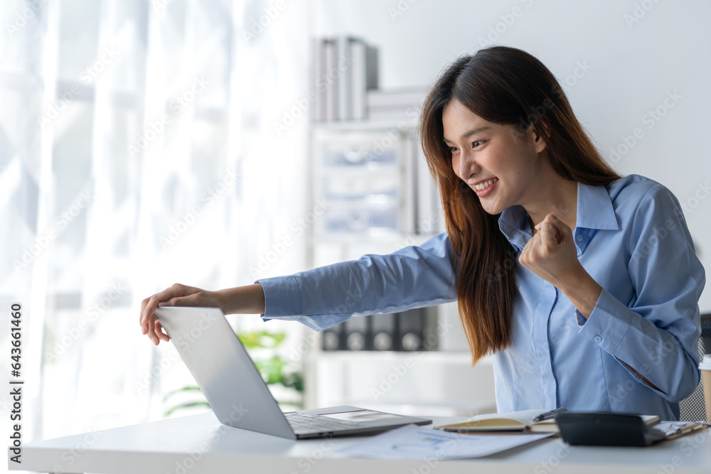 Happy young asian businesswoman sitting on her workplace in the office. Young woman working at laptop in the office Happy young asian businesswoman sitting on her workplace in the office. Young woman working at laptop in the office