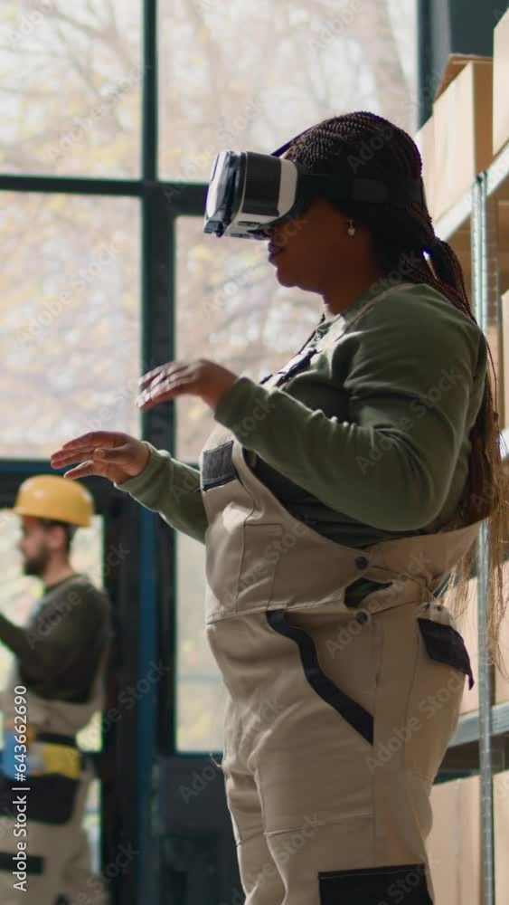 Vertical video Manager in warehouse wearing VR goggles, using technology to visualize how to best stack cardboard boxes on shelves to make room for more. Supervisor in storage hub uses virtual reality Vertical video Manager in warehouse wearing VR goggles, using technology to visualize how to best stack cardboard boxes on shelves to make room for more. Supervisor in storage hub uses virtual reality