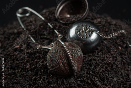 Loose tea and Tea sieve on a black background.