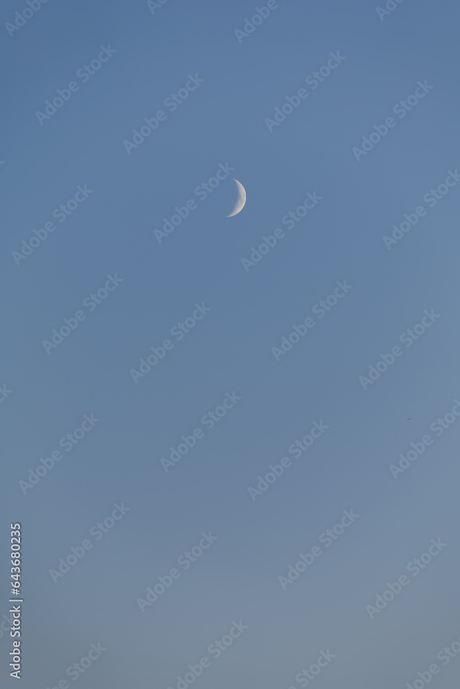 Bright Crescent Moon in Blue Afternoon Sky Background Bright Crescent Moon in Blue Afternoon Sky Background