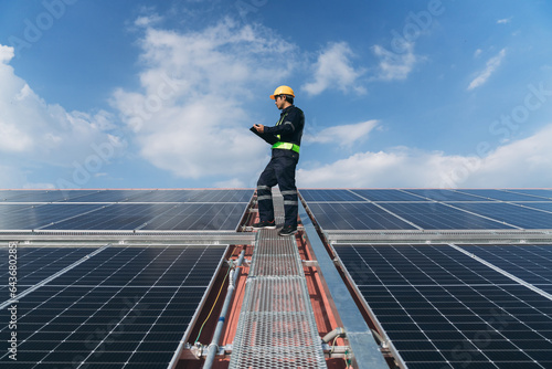 A service engineer checks a solar cell that is mounted on the roof to see if there is a damaged component that needs to be repaired. Concept of energy from natural sources.