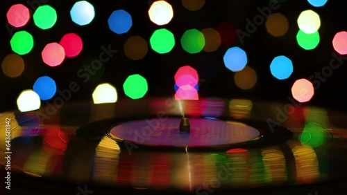 Turntable against the background of multi-colored spots in the dark, close-up
