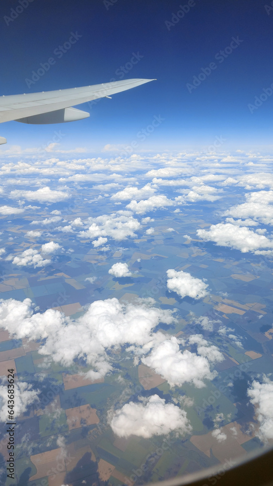 Beautiful view from above to the ground from the window of an airplane flying above the clouds. Shadows from clouds on the Earth's surface Beautiful view from above to the ground from the window of an airplane flying above the clouds. Shadows from clouds on the Earth's surface