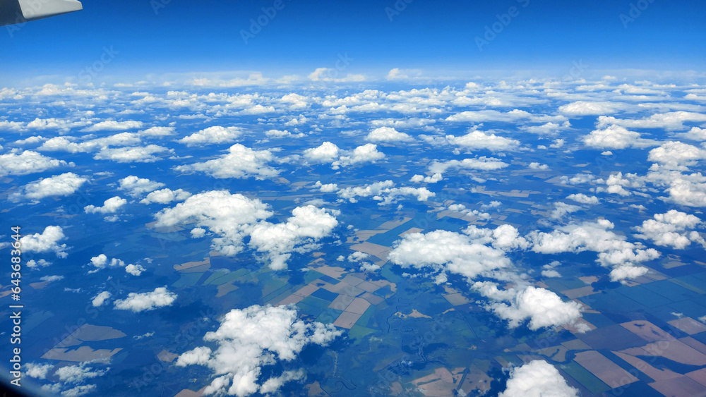 Fototapeta premium Beautiful view from above to the ground from the window of an airplane flying above the clouds. Shadows from clouds on the Earth's surface