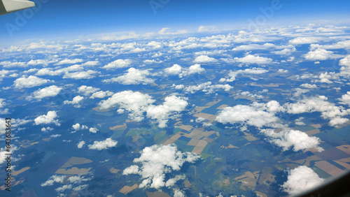 Beautiful view from above to the ground from the window of an airplane flying above the clouds. Shadows from clouds on the Earth's surface