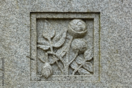 Stone carving of flowers on grave stone in cemetery.