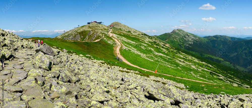 Mountain landscape on a hiking trail in the Low Tatras, Slovakia. View of mountain peaks and valleys while hiking along a mountain ridge. Slopes covered with alpine vegetation, summer sunny day.