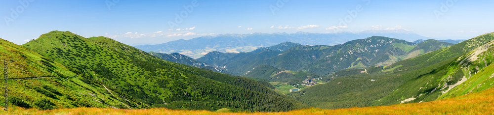 Mountain landscape on a hiking trail in the Low Tatras, Slovakia. View of mountain peaks and valleys while hiking along a mountain ridge. Slopes covered with alpine vegetation, summer sunny day.