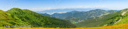Mountain landscape on a hiking trail in the Low Tatras, Slovakia. View of mountain peaks and valleys while hiking along a mountain ridge. Slopes covered with alpine vegetation, summer sunny day. © Castigatio