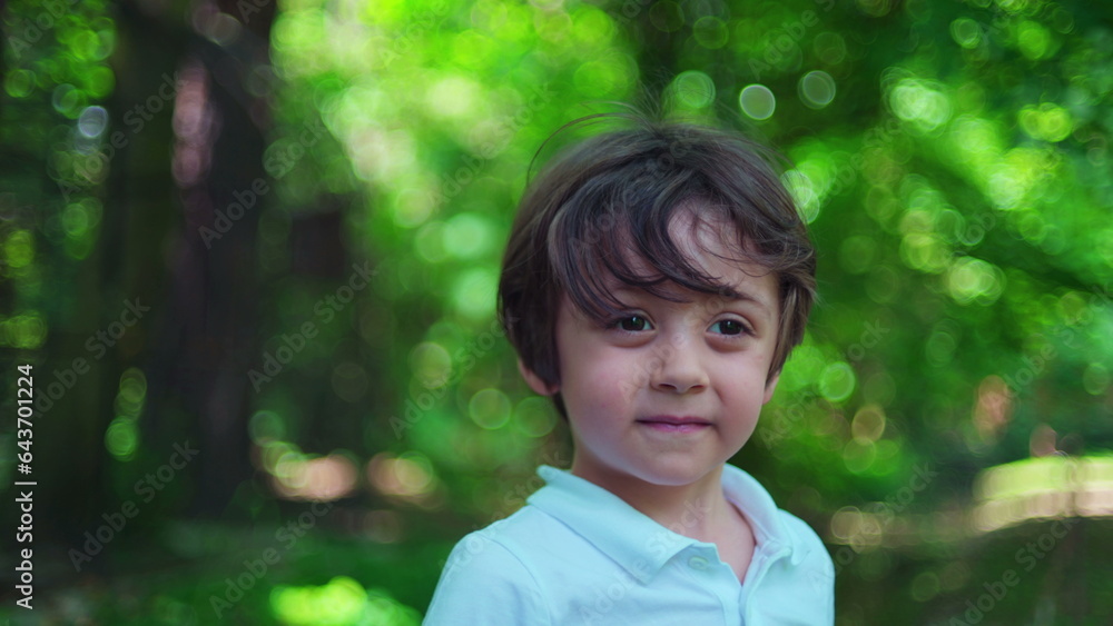 Bright Day Park Portrait/ Little Boy Faces Camera Amidst Lush Greenery Bright Day Park Portrait/ Little Boy Faces Camera Amidst Lush Greenery