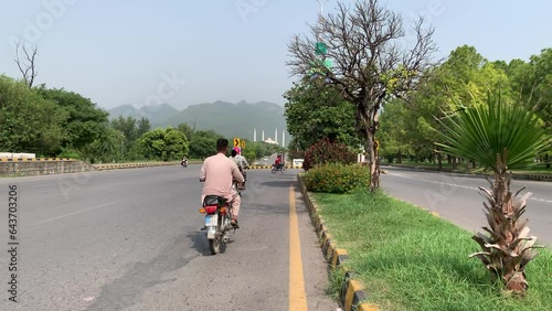 View of Faisal Mosque and mountains from the road, Cars are going on the road, trees around the road. Islamabad Pakistan 02 September 2023. photo
