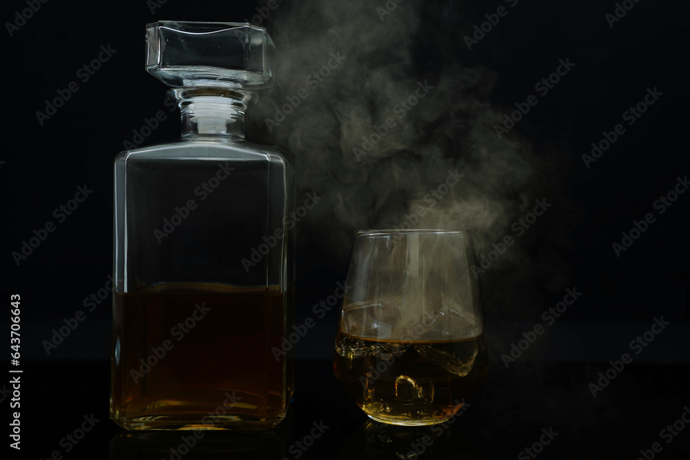 Cocktail whiskey drink on ice isolated at black with smoke