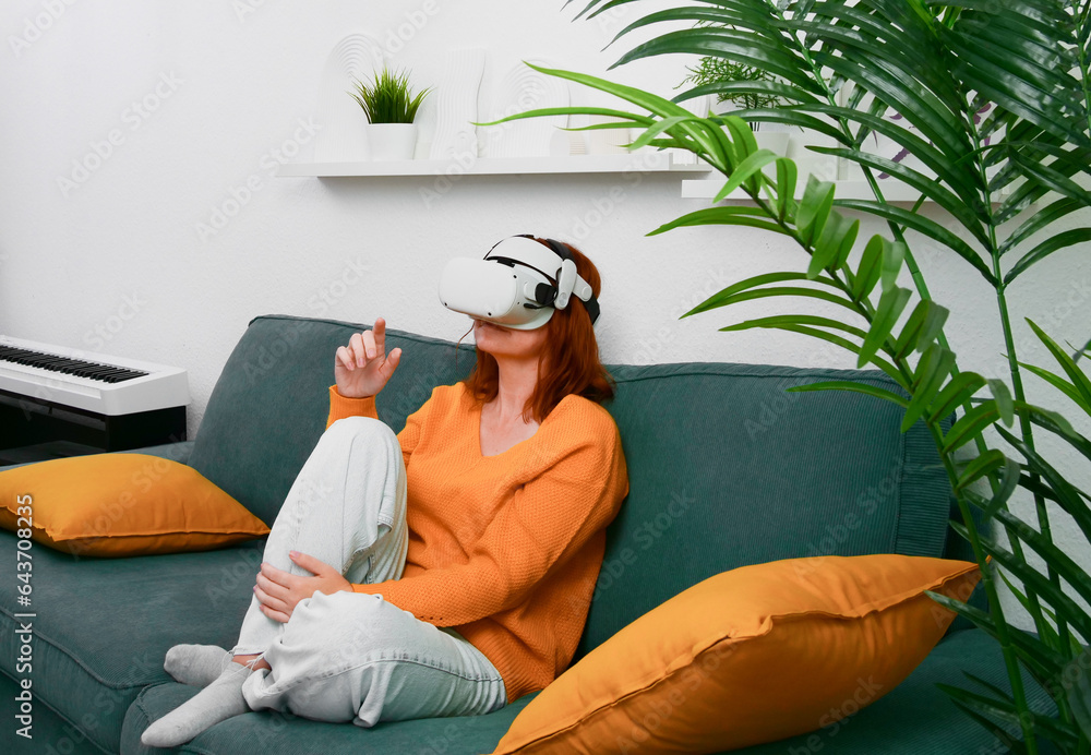 woman sitting on sofa relaxing and playing VR and using futuristic artificial intelligence at home.. the concept of metaverse, virtual reality, future, technology, and internet of things.