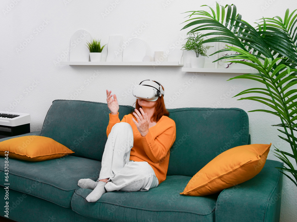 woman sitting on sofa relaxing and playing VR and using futuristic artificial intelligence at home.. the concept of metaverse, virtual reality, future, technology, and internet of things.