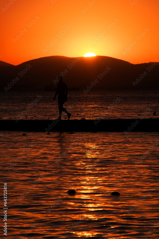 Inspirational tropical beach landscape. Orange and golden sunset sky with man silhouette, calmness, relaxing sunlight, summer mood. Vacation travel banner