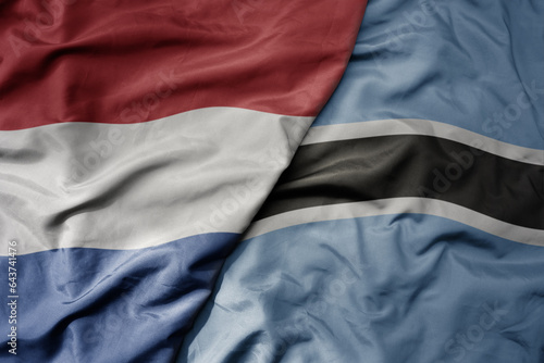 big waving national colorful flag of netherlands and national flag of botswana .