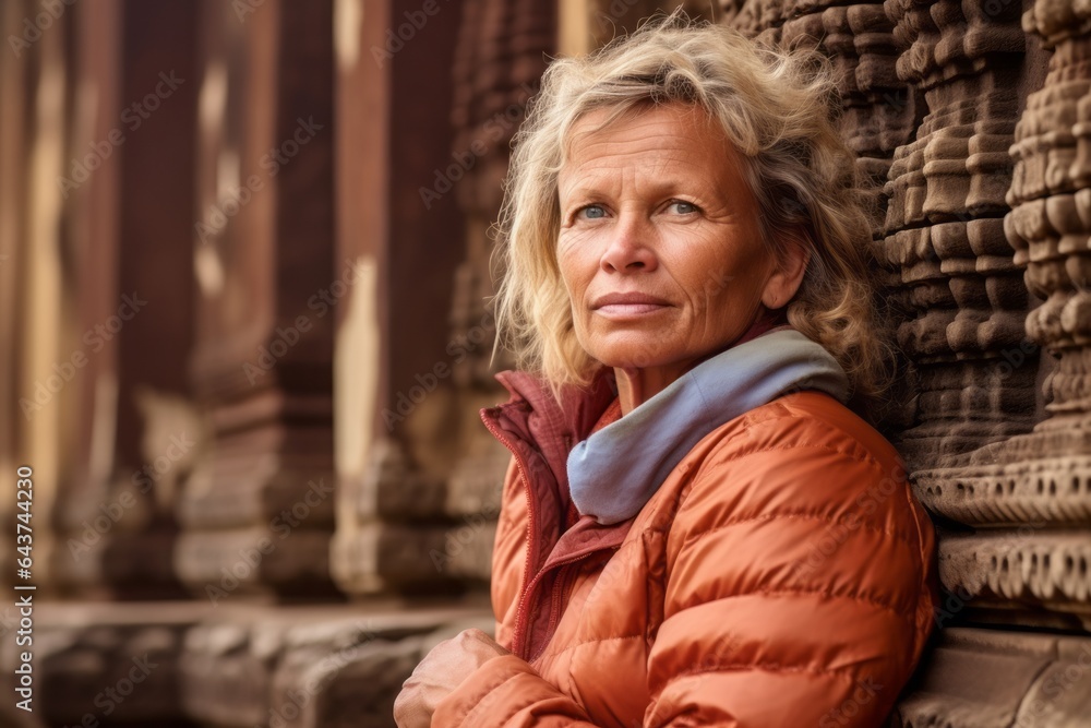 Naklejka premium Medium shot portrait photography of a glad mature woman wearing a quilted insulated jacket at the angkor wat in siem reap cambodia. With generative AI technology